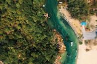 航拍画面令人惊叹，展示了郁郁葱葱的森林、蜿蜒的河流以及停泊着船只的沙质海岸