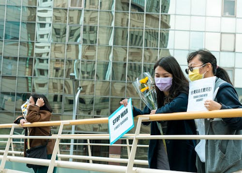 Women Holding Yellow Flowers and Anti-War Signs