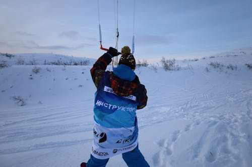 Person in Blue and White Jacket and Black Pants Riding Ski Blades on Snow Covered Ground