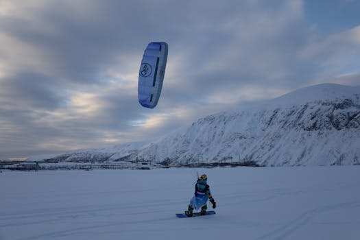 Person snowkiting in Kirovsk, Russia, with snow-covered mountains in the background.