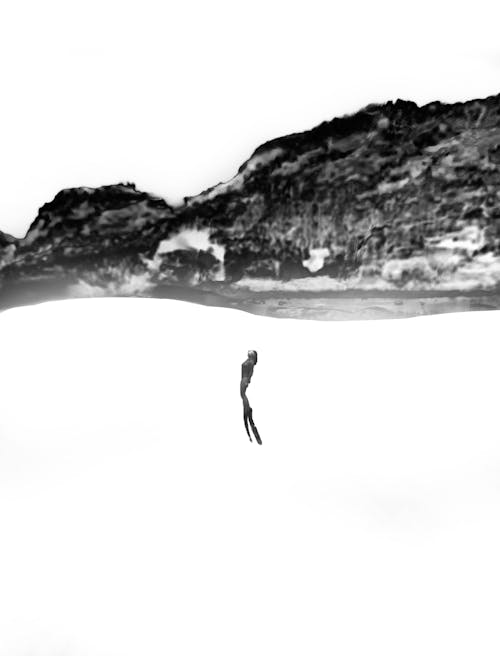 A Grayscale of a Woman Swimming towards the Surface of the Water