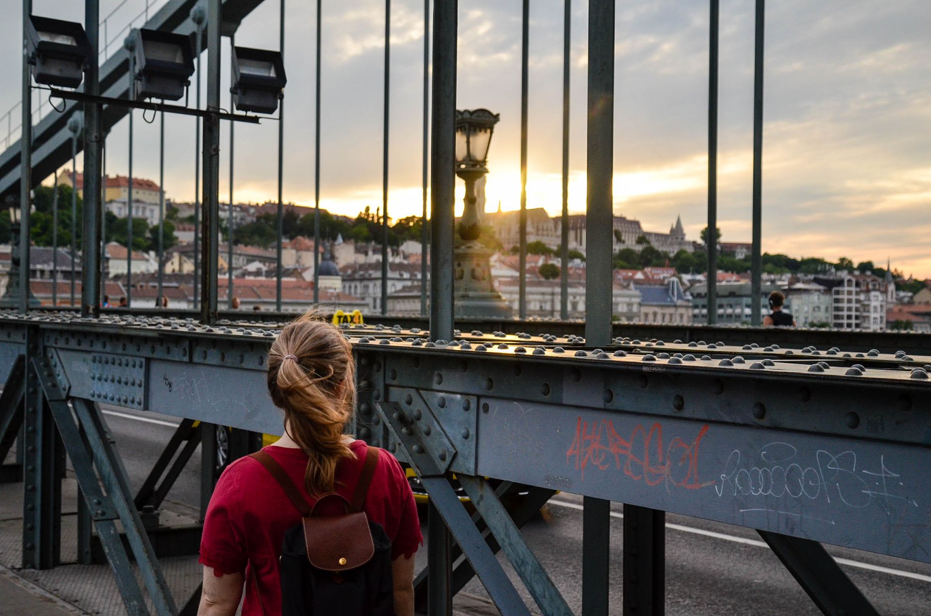 Person on a bridge in Budapest watching sunset over historic city skyline
