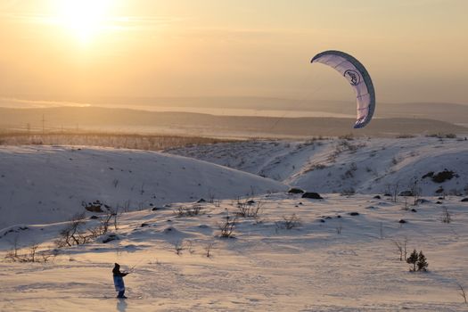 A kiteboarder enjoys snowkiting in the winter landscape of Murmansk, Russia.