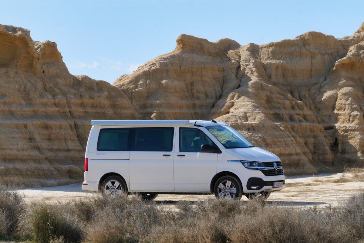 Un camper van bianco che guida attraverso un paesaggio desertico roccioso