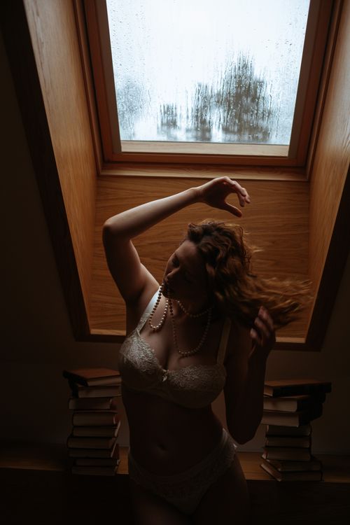 Free Stylish photo of a woman posing in lingerie near a skylight, creating a moody and artistic atmosphere. Stock Photo