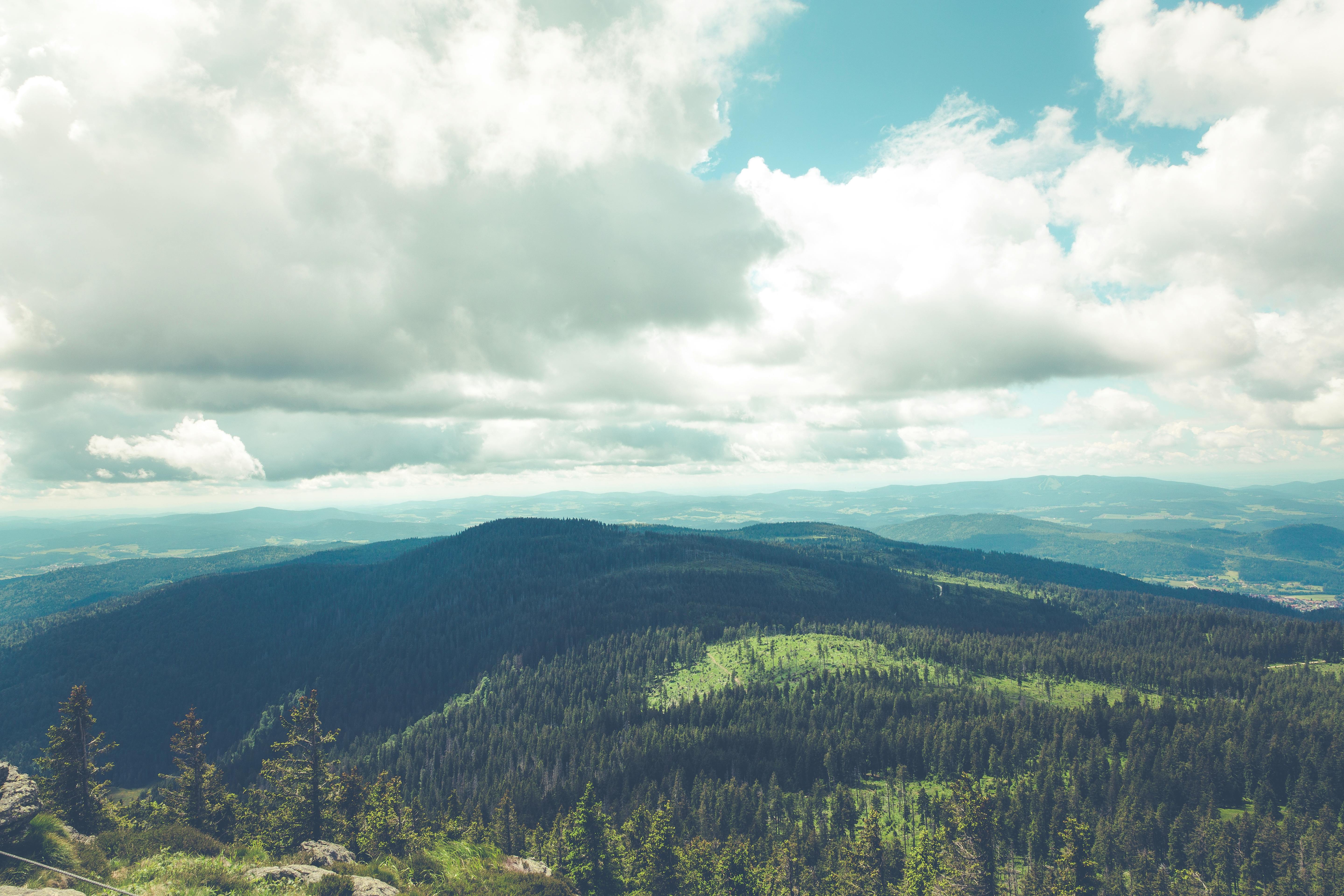 一座惊人的山脉与茂密的森林上空，戏剧性的多云天空笼罩着