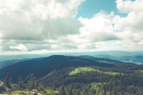 Free A breathtaking view of a mountain range with lush forests under a dramatic cloudy sky. Stock Photo