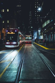 A vibrant night view of streetcars in downtown Toronto, showcasing urban transportation.