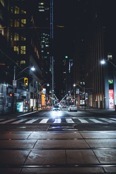 A lively street scene in Toronto at night, featuring traffic and city lights.