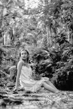 Grayscale portrait of a woman in a forest setting, exuding elegance and calm.