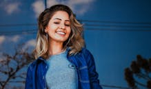 背景是蓝天，户外一位年轻女子微笑的肖像