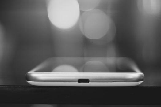A sleek smartphone captured in a black and white bokeh setting, showcasing minimalist design.