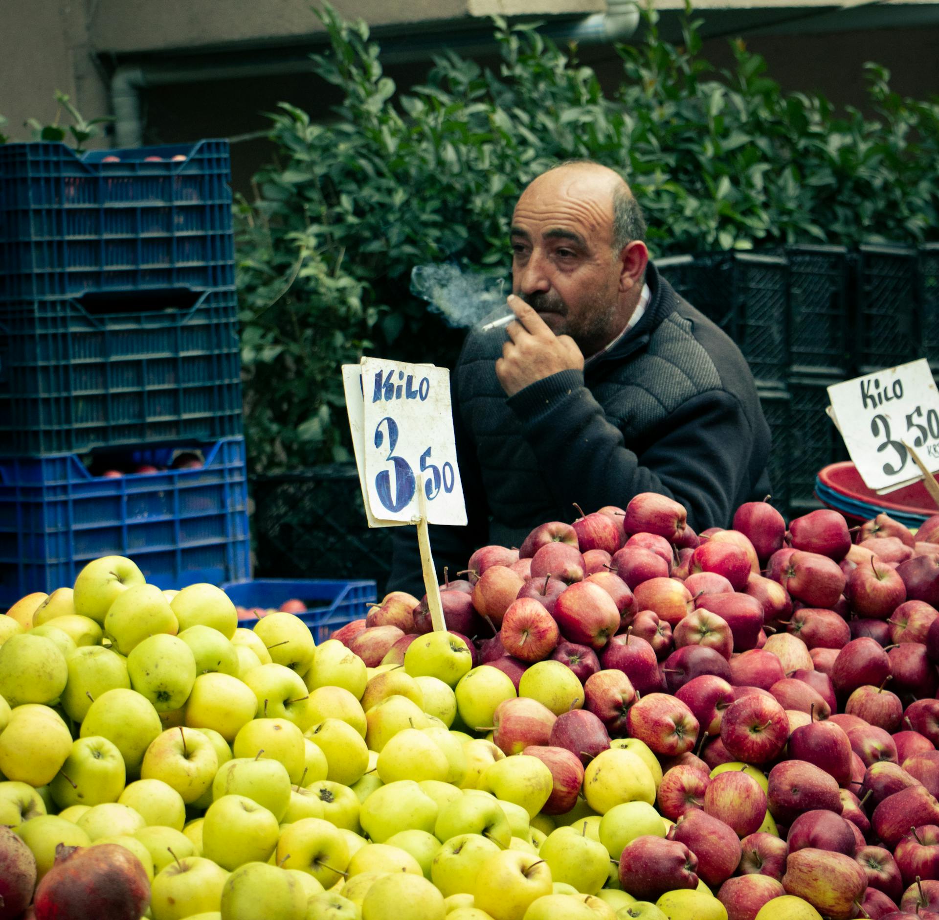 A street vendor in Istanbul selling apples at a market stall while smoking.