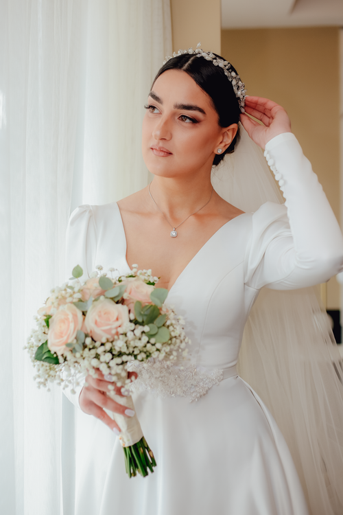 Free A beautiful bride holding a floral bouquet in a white gown, radiating elegance and grace. Stock Photo