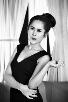 Stylish woman posing gracefully indoors in elegant black dress.
