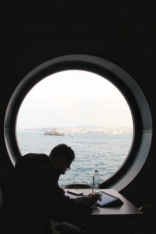 A Man Sitting Beside the Glass Window