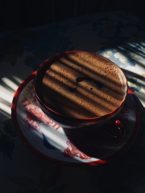 A close-up shot of a steaming cup of Kopi Gu Yu, with visible layers of coffee and tea.