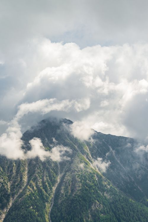 Free A stunning view of a green mountain peak veiled by dramatic clouds, capturing nature's beauty. Stock Photo