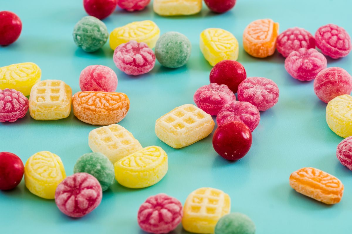 A vibrant collection of colorful candies scattered on a blue background, perfect for sweets lovers.