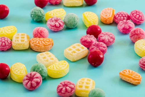 Free A vibrant collection of colorful candies scattered on a blue background, perfect for sweets lovers. Stock Photo
