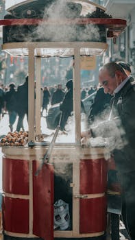 Street vendor roasting chestnuts on a busy Istanbul street, showcasing local culture and cuisine.