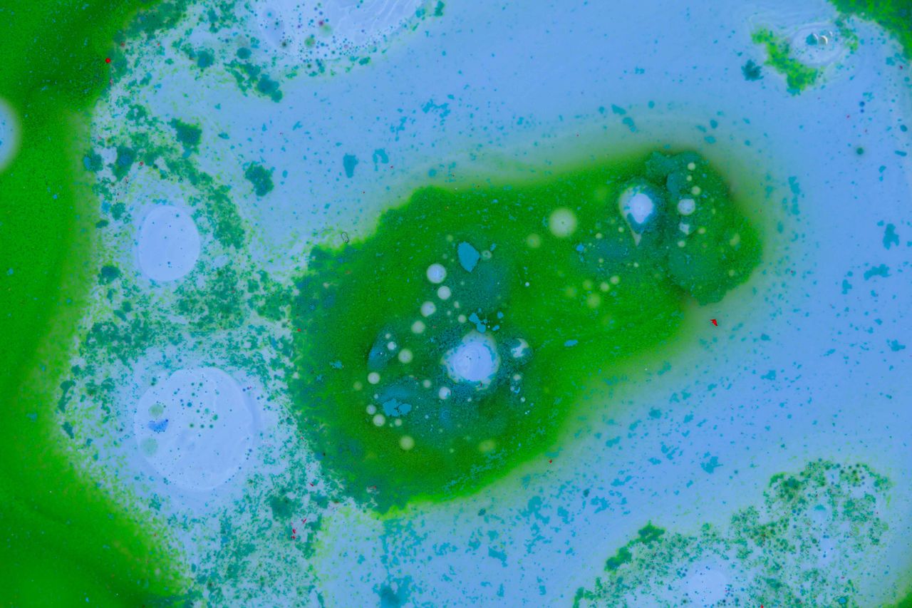 an abstract image featuring a vibrant mix of green and blue paint crea