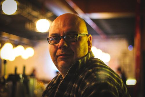 Free Bald man wearing glasses in a warm-lit café, captured with shallow depth of field. Stock Photo