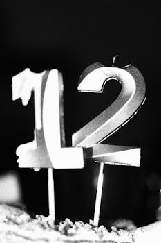A close-up black and white photo of number 12 candles on a cake.
