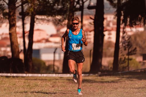 Free Athlete in blue jersey running on a grassy field during a sport event. Stock Photo