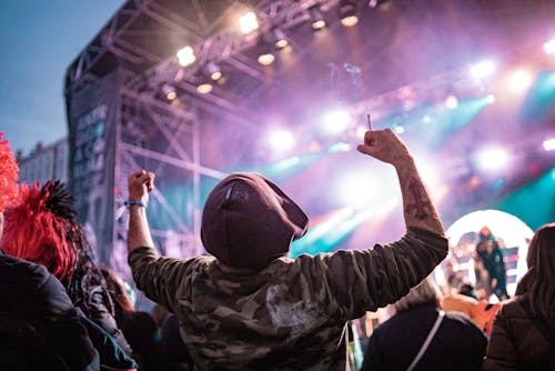 Back View of a Man with a Cigarette in Hand Having Fun at a Concert