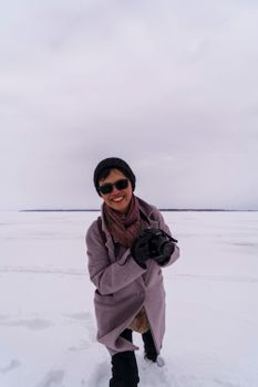 A joyful photographer with a camera enjoying a winter day outdoors in the snow.