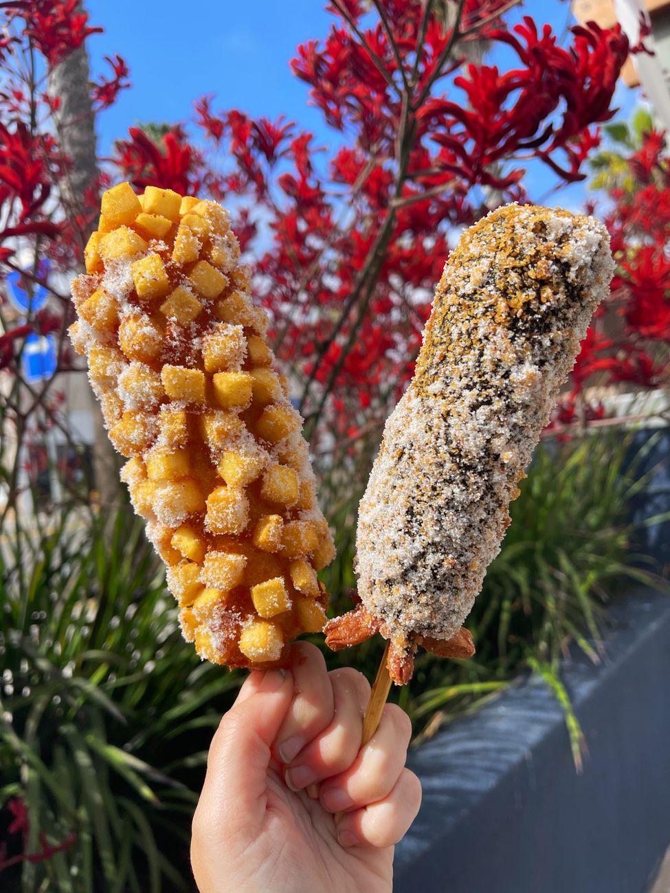 Golden Korean corn dogs drizzled with glossy red gochujang sauce on a street food serving tray
