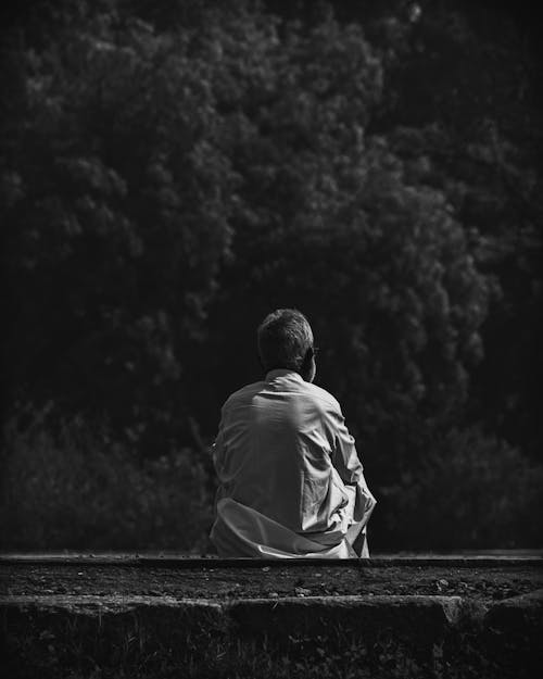 Grayscale Photo of a Man Sitting