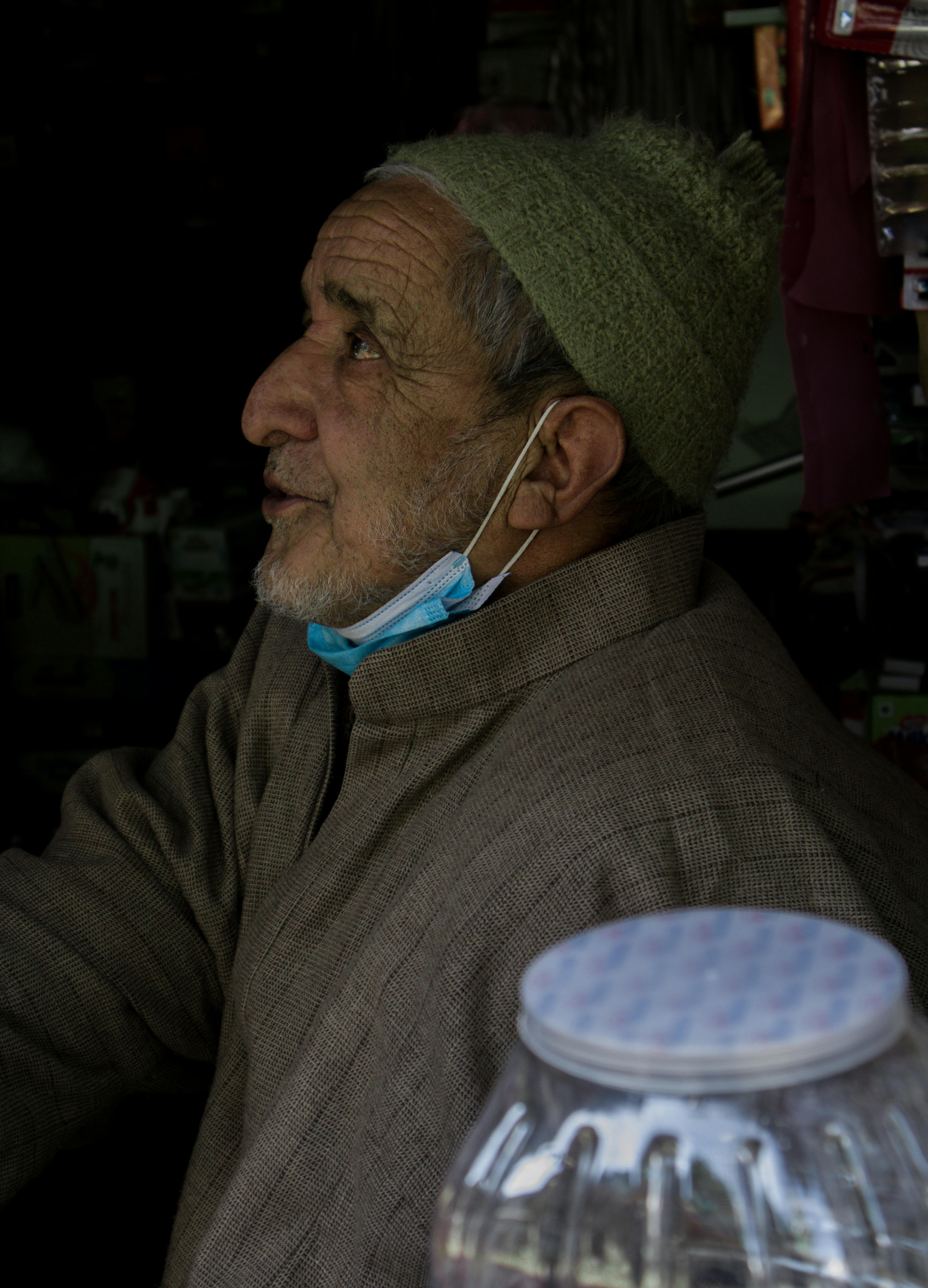 portrait of elderly man wearing face mask on his chin