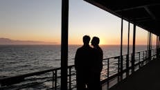 甲板上一对夫妇的剪影，正欣赏着海洋上令人惊叹的日落