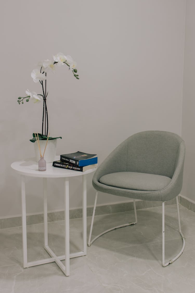 White Flower On A White Table Beside A Grey Chair 