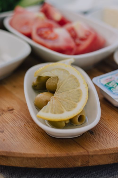 Free Close-up of fresh lemon slices and olives on a wooden board, perfect for food photography. Stock Photo