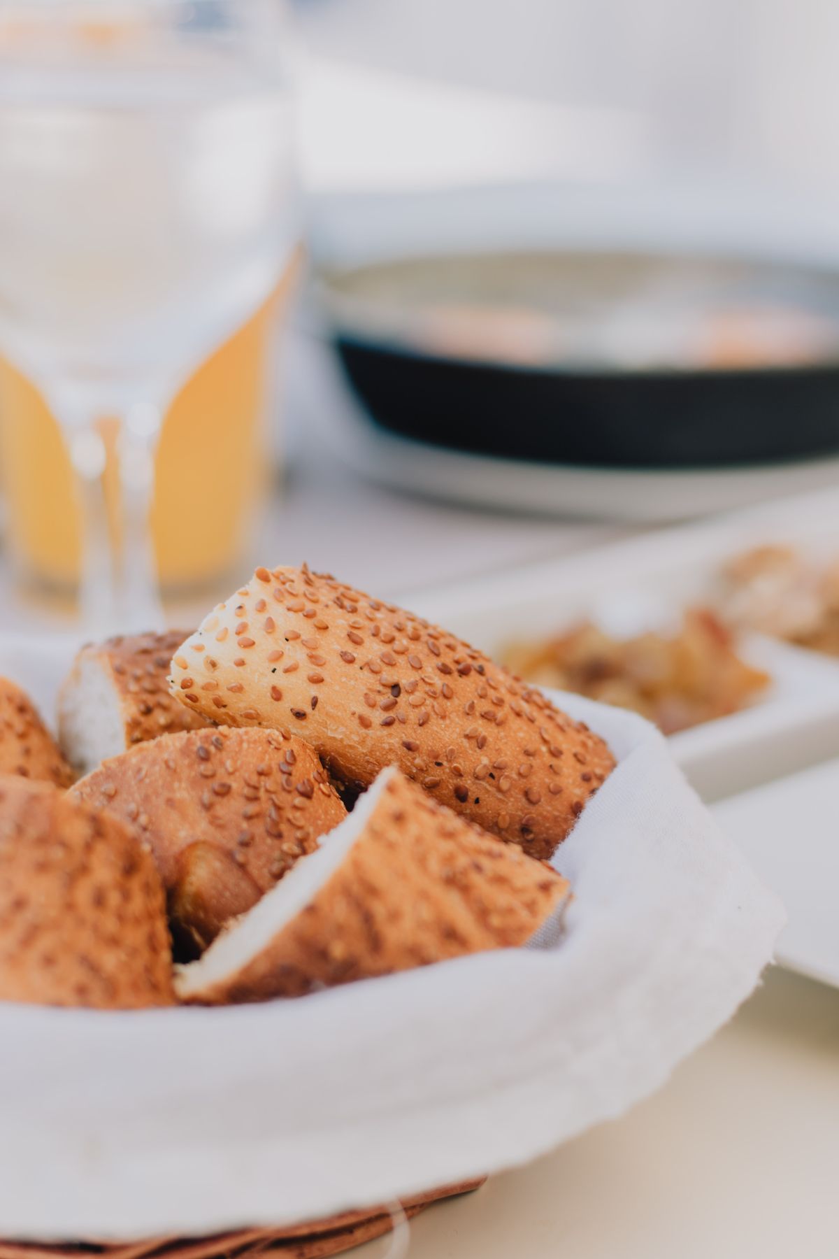 A close-up of sesame and seed-topped bread in a basket on a table.