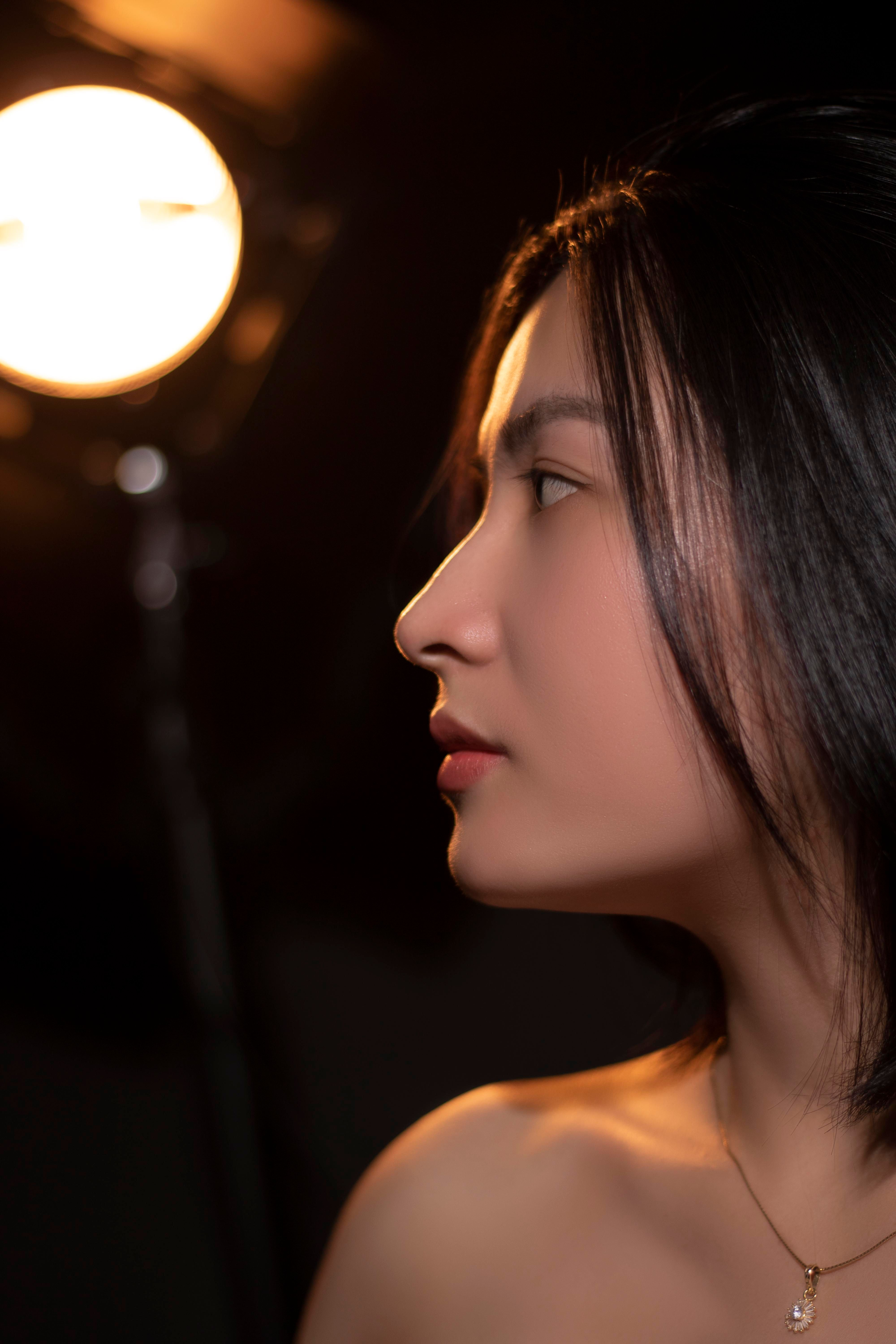 A beautiful side profile portrait of a young woman under studio lighting, exuding elegance and poise
