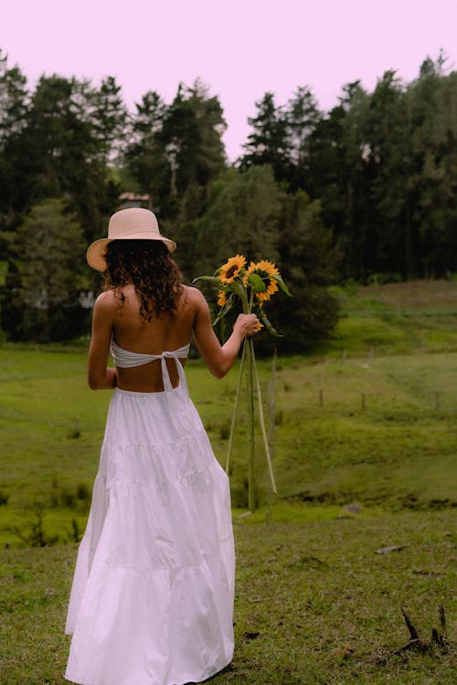 Free Woman in White Dress Holding Yellow Flowers Stock Photo