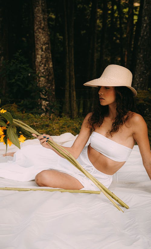 A Woman in White Tube Sitting on White Blanket