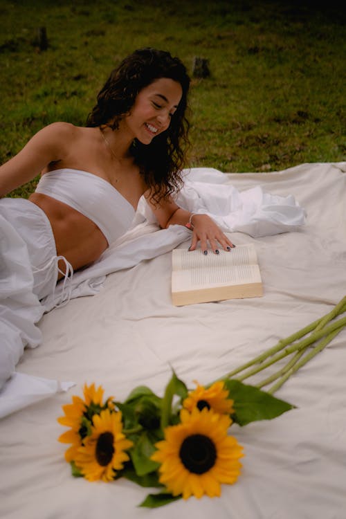 Free A Woman in White Tube Top Reading a Book Stock Photo