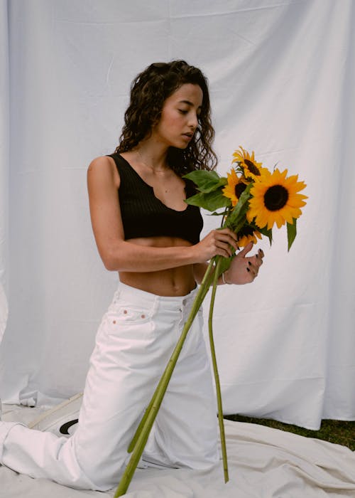 Free Woman in Black Crop Top Holding Sunflowers Stock Photo