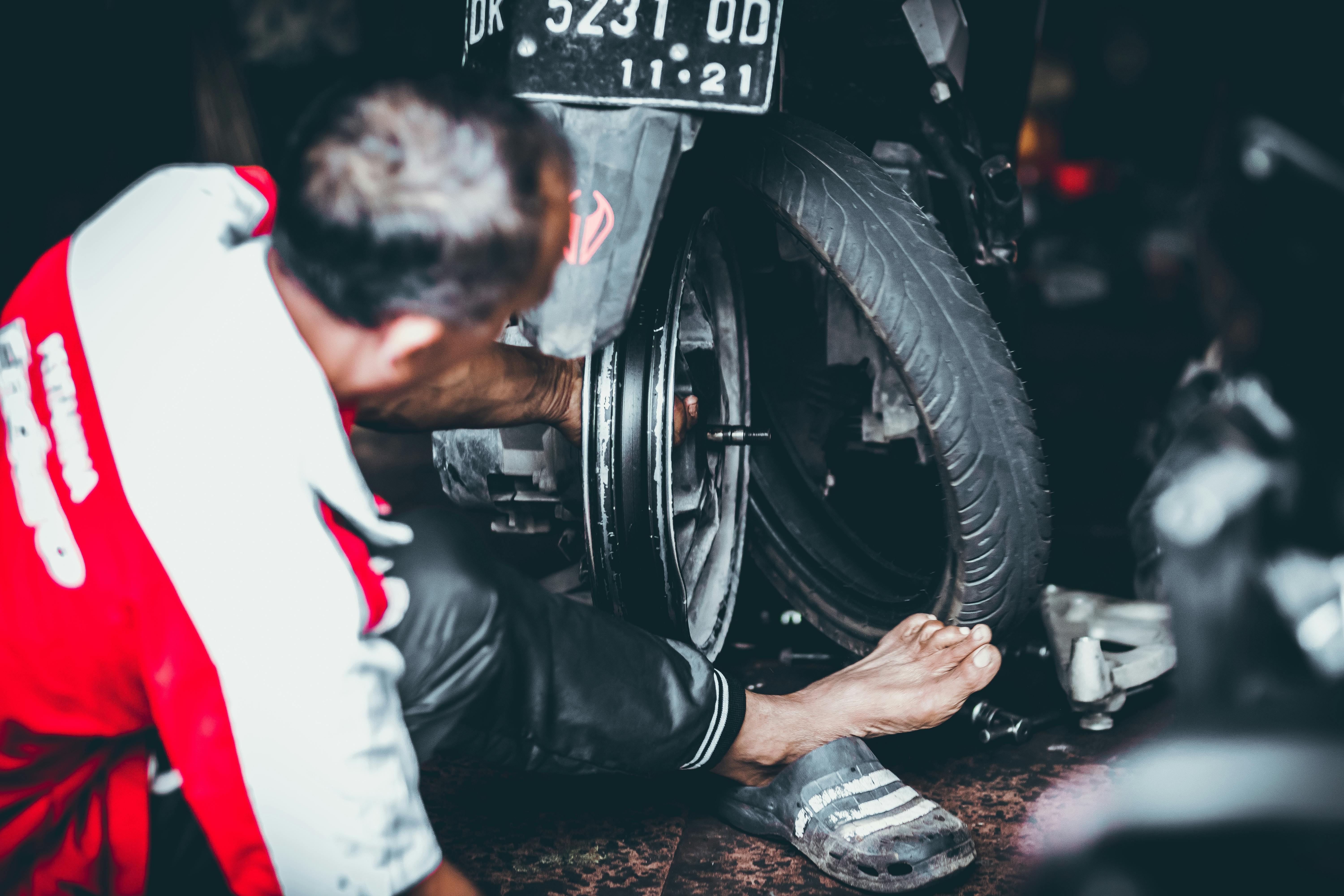 Man Changing a Rear Tire of a Motor Scooter