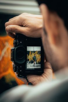 Close-up of a photographer holding a camera capturing an artsy scene.