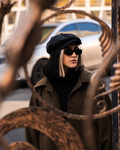 A Woman in Brown Coat Wearing Sunglasses and a Hat on the Street