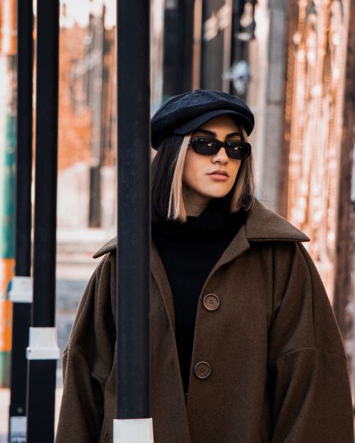 Free Fashionable young woman wearing a black beret and sunglasses, strolling on a city street in Tabriz. Stock Photo