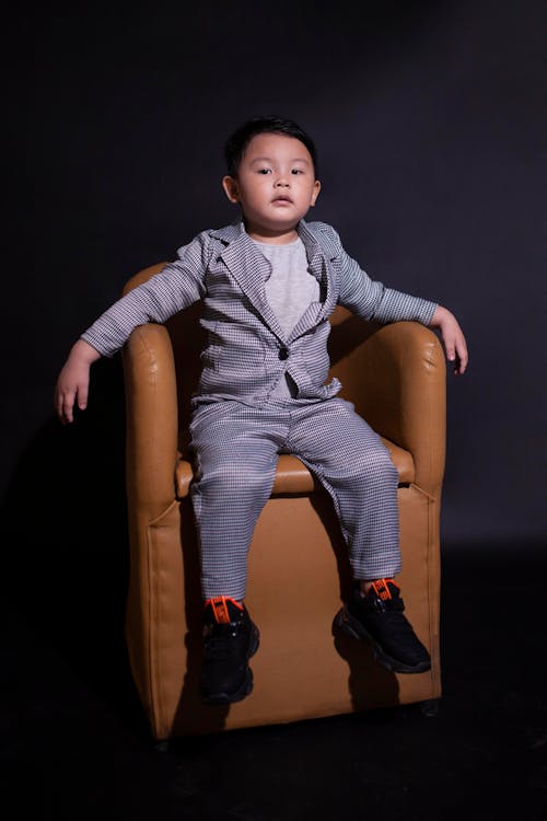 Boy Wearing a Suit Sitting on Brown Sofa Chair