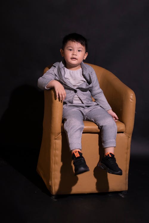 Free A Cute Baby Boy Sitting on a Brown Leather Chair Stock Photo