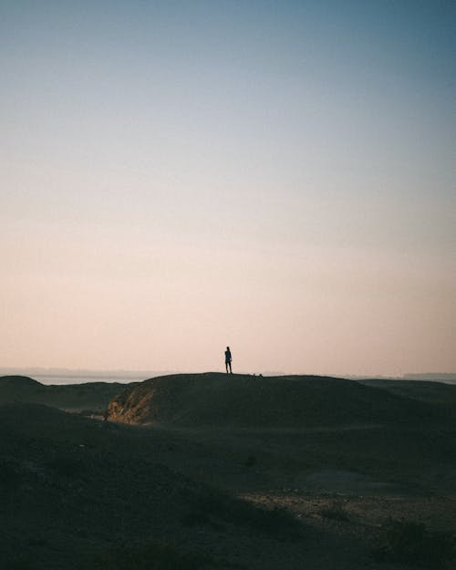 Silhouette of a Person Standing on the Mountain